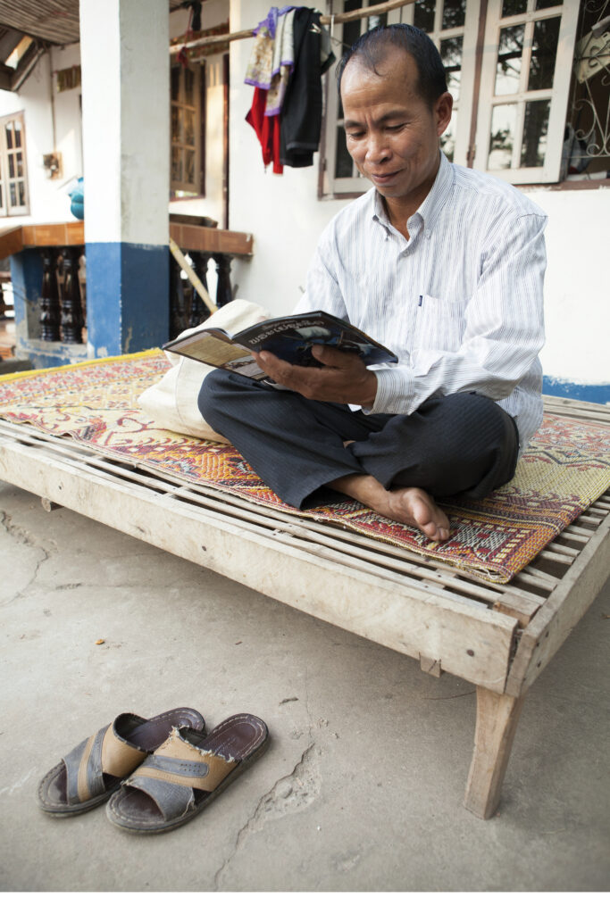 a man sits on a wood platform and reads his bible