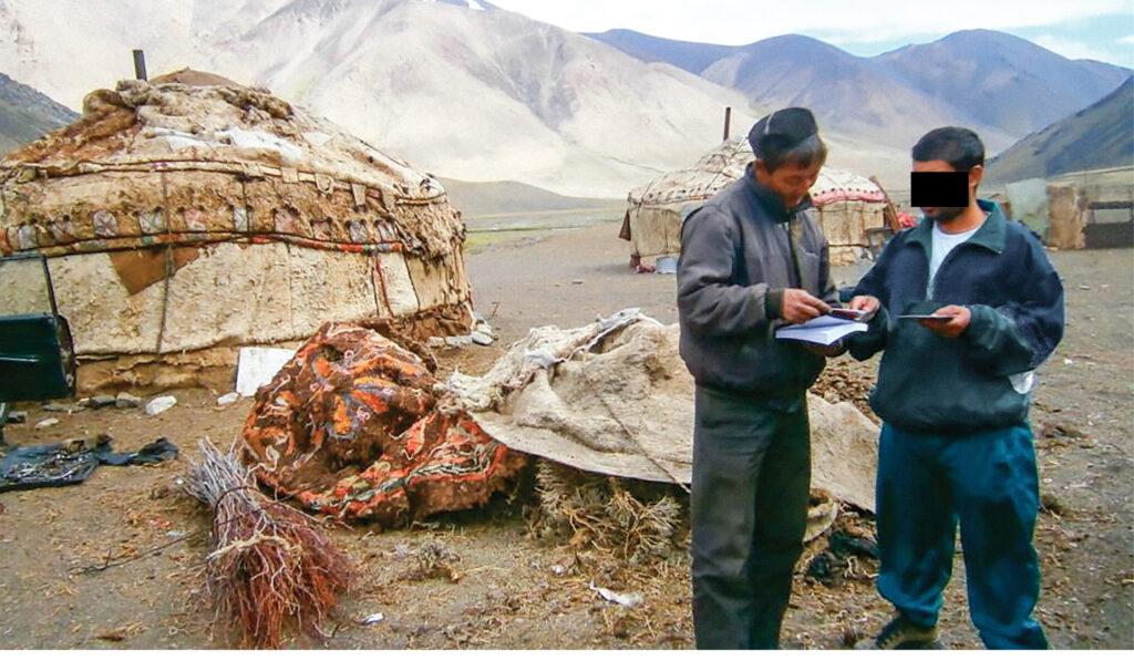 Two men stand by a tent outside looking at a map