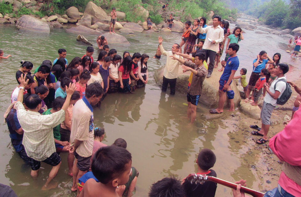 A large group of people worshipping in a river