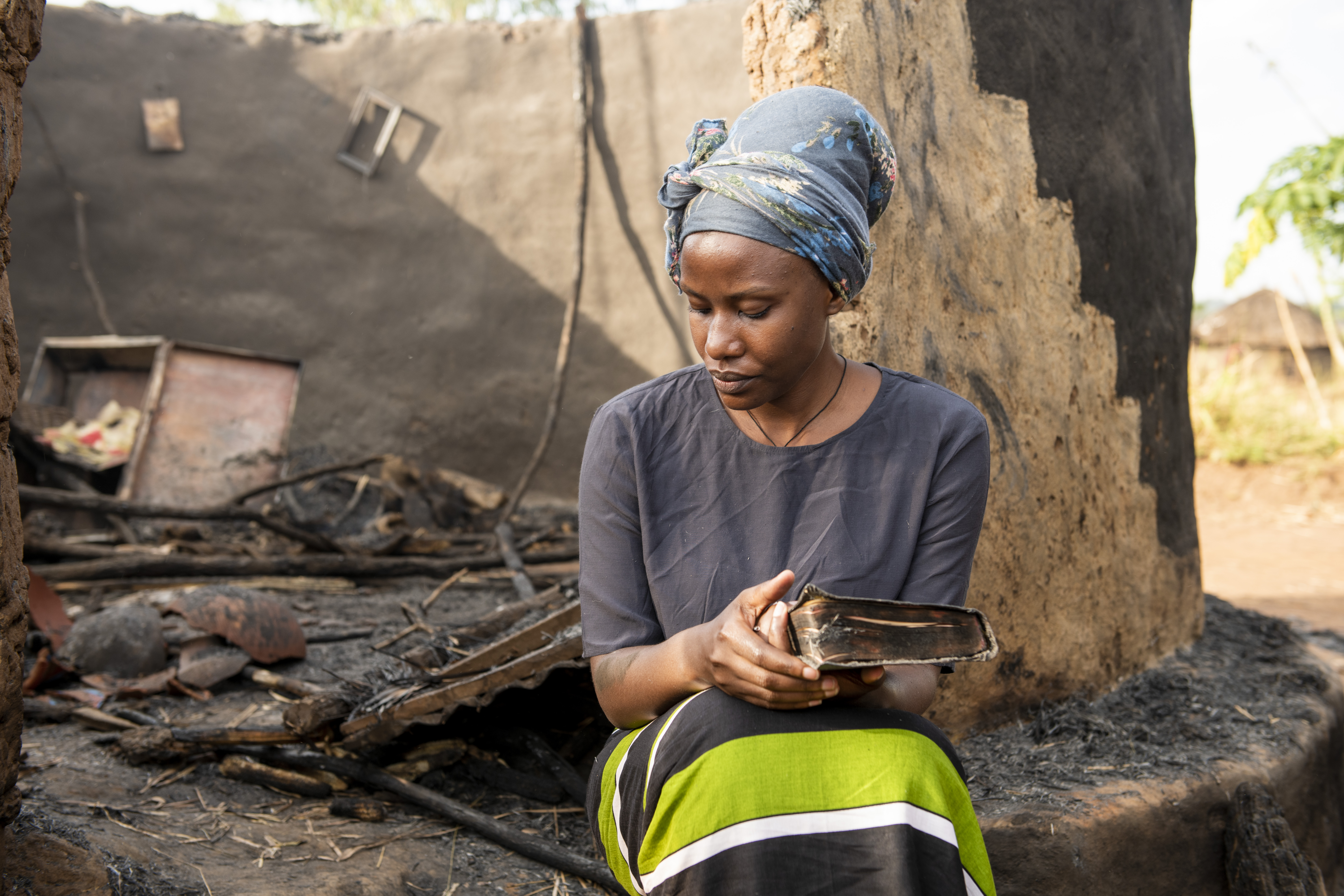 Woman sitting by her burned home. President's Letter Story.