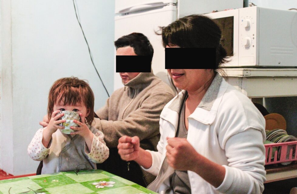 a husband and wife sit with their daughter at their kitchen table