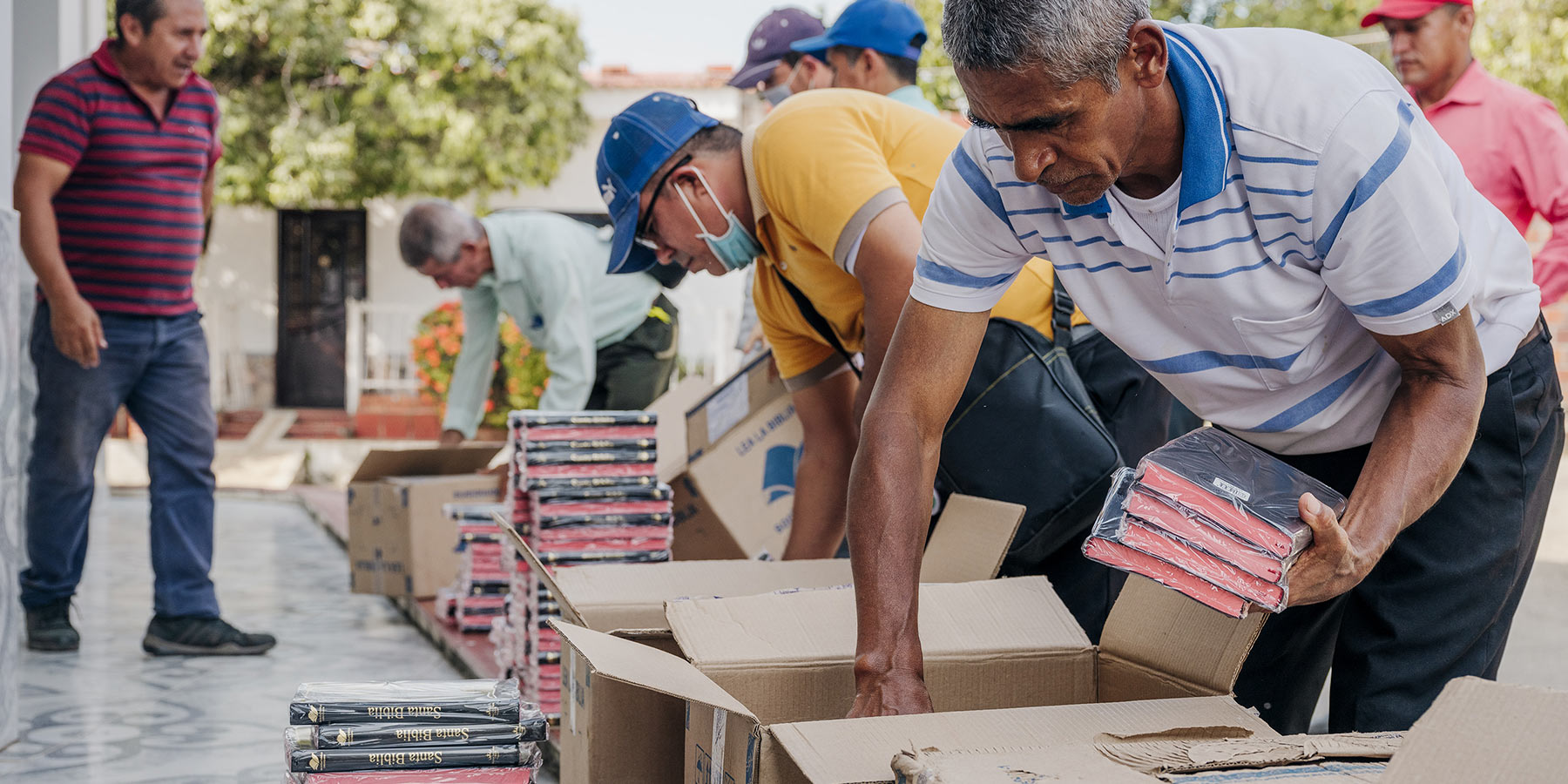 People putting plastic wrapped Bibles in boxes.